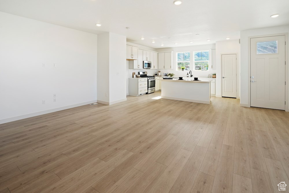 Unfurnished living room with light wood-type flooring and sink