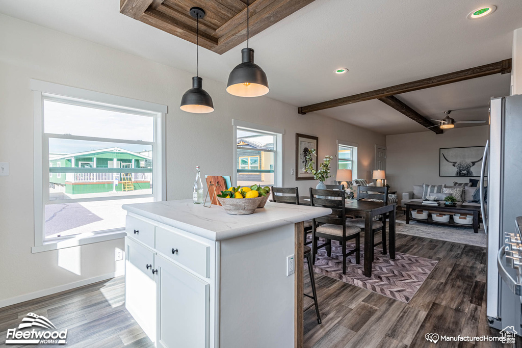 Kitchen featuring light stone counters, dark hardwood / wood-style floors, white cabinets, a center island, and decorative light fixtures