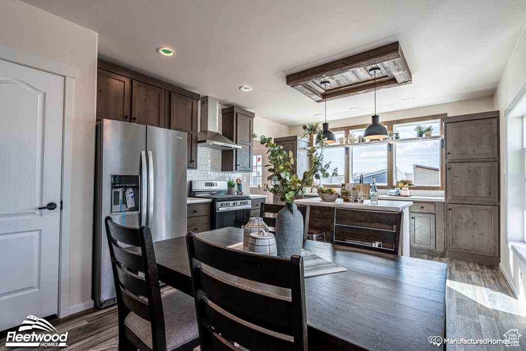 Kitchen with tasteful backsplash, dark hardwood / wood-style floors, dark brown cabinets, wall chimney exhaust hood, and stainless steel appliances