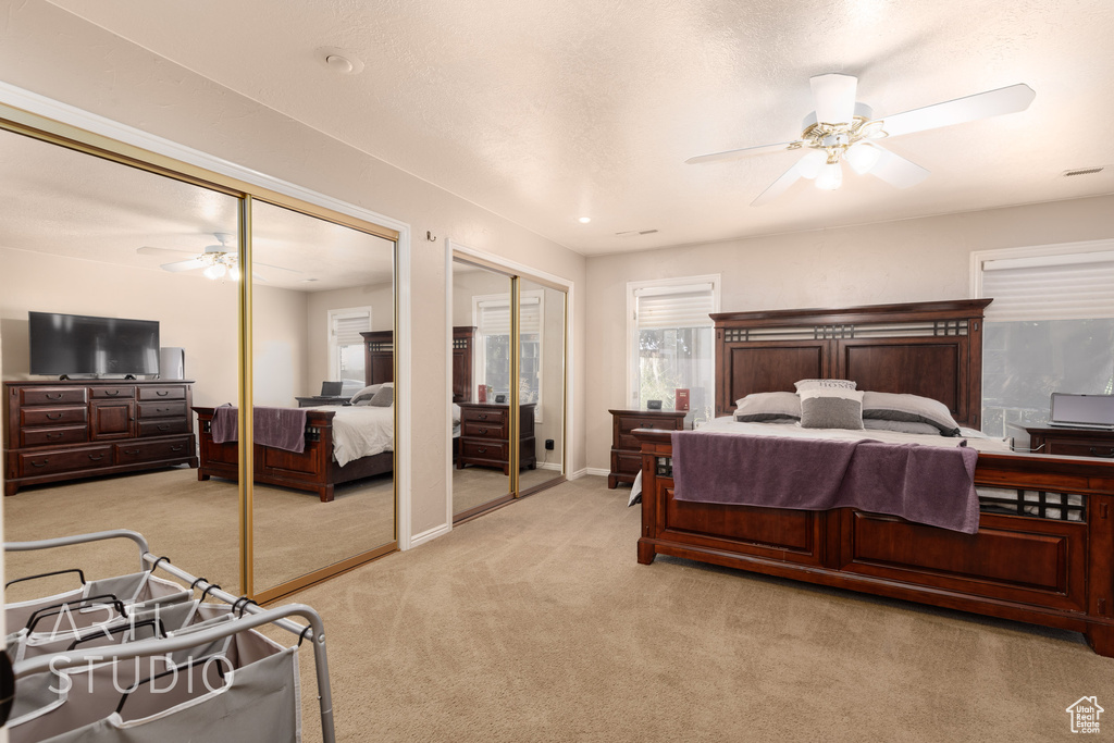 Carpeted bedroom with multiple closets and ceiling fan