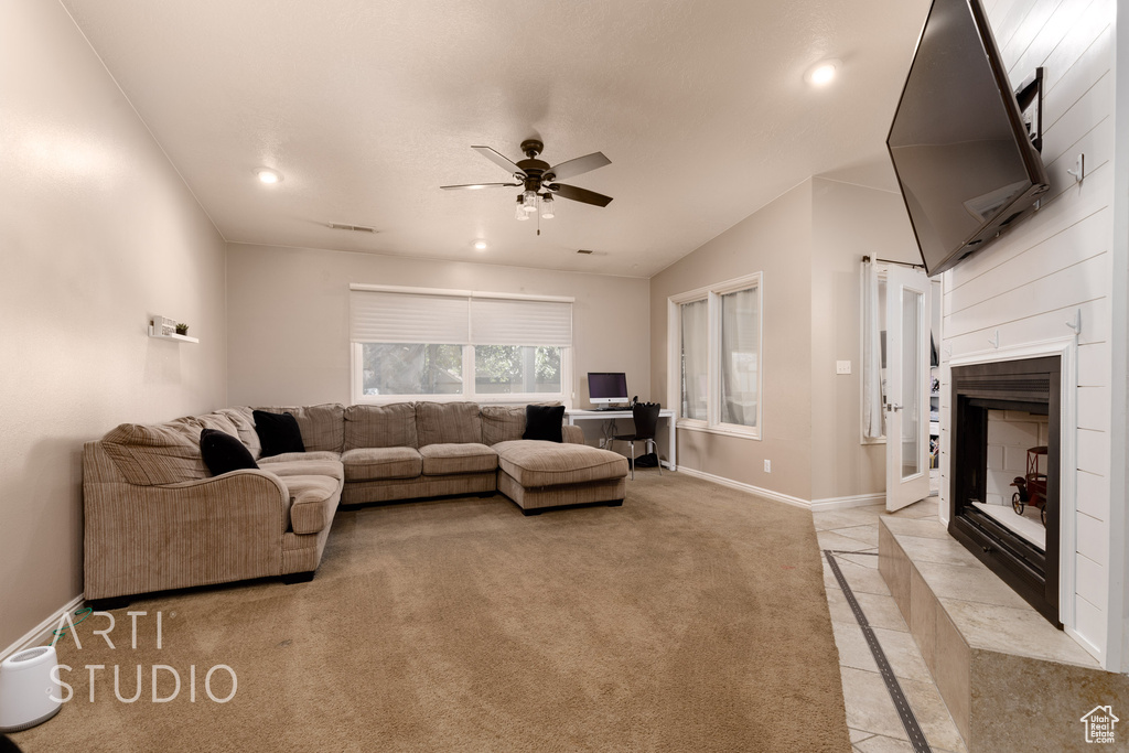 Carpeted living room featuring ceiling fan and a fireplace