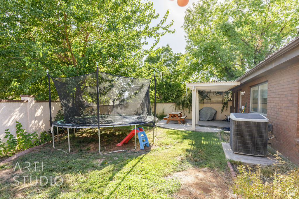 View of yard with cooling unit, a patio area, and a trampoline