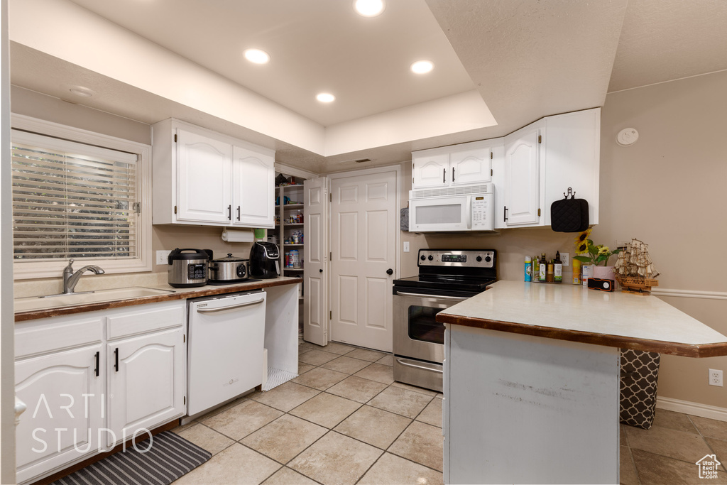 Kitchen with sink, white cabinetry, white appliances, and light tile patterned floors