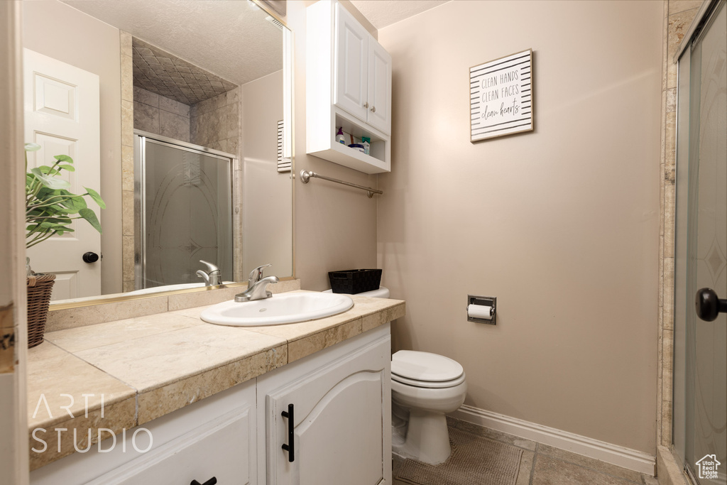 Bathroom with a shower with door, toilet, tile patterned floors, and vanity