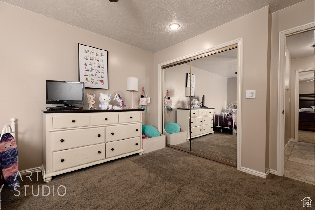 Carpeted bedroom featuring a textured ceiling and a closet