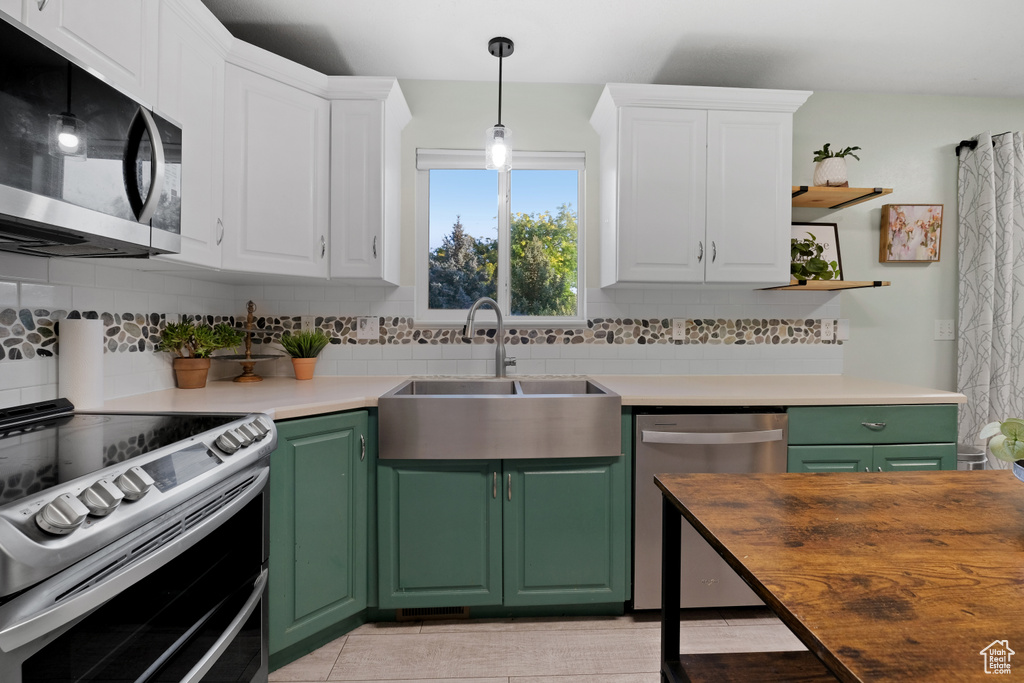 Kitchen featuring sink, stainless steel appliances, white cabinetry, and green cabinets