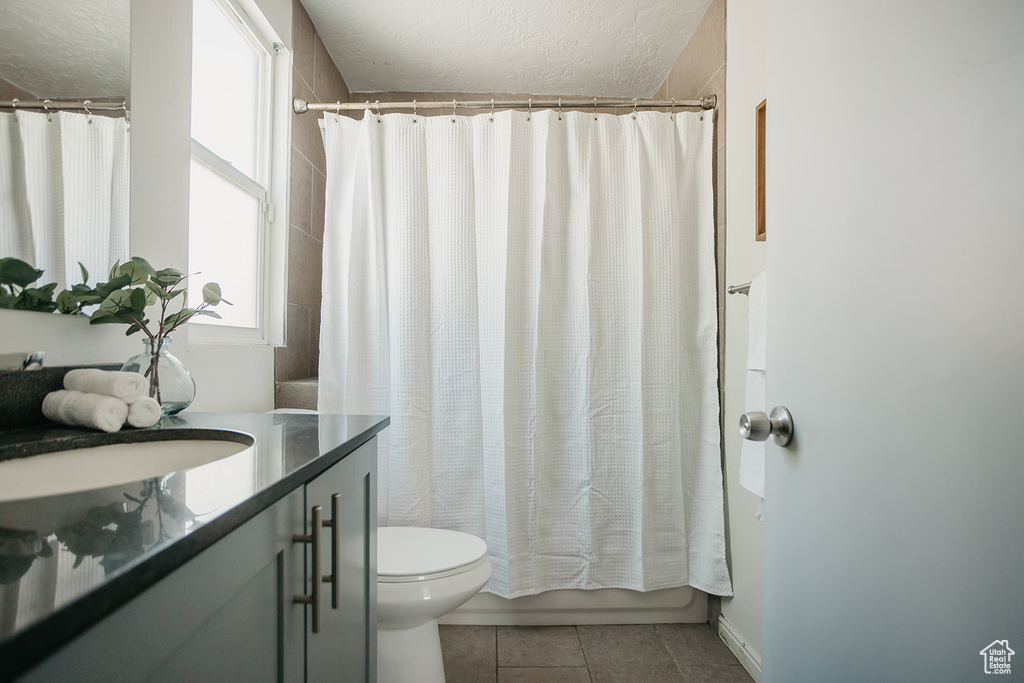 Bathroom with toilet, tile patterned floors, and vanity