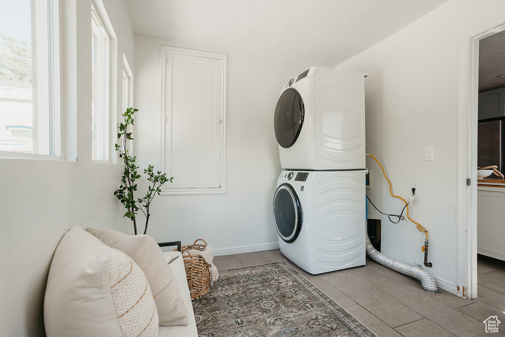 Laundry room with stacked washer and dryer and light tile patterned floors