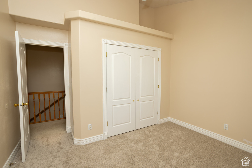 Unfurnished bedroom featuring light carpet and a closet