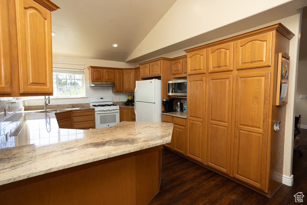 Kitchen with sink, dark hardwood / wood-style flooring, light stone countertops, white appliances, and tasteful backsplash