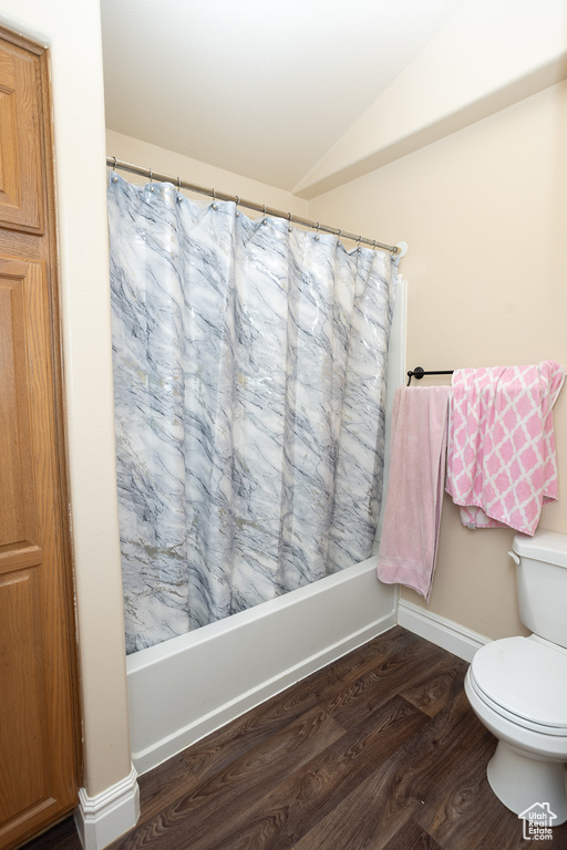 Bathroom with toilet, vaulted ceiling, wood-type flooring, and shower / bath combo