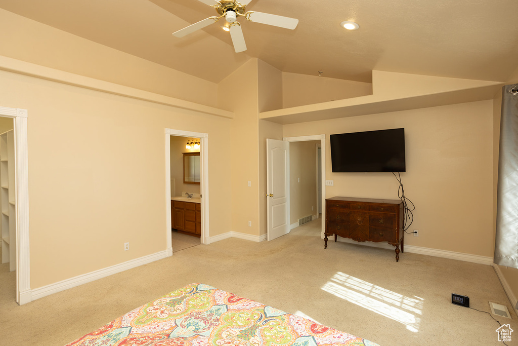 Unfurnished bedroom with high vaulted ceiling, ceiling fan, light colored carpet, and ensuite bathroom