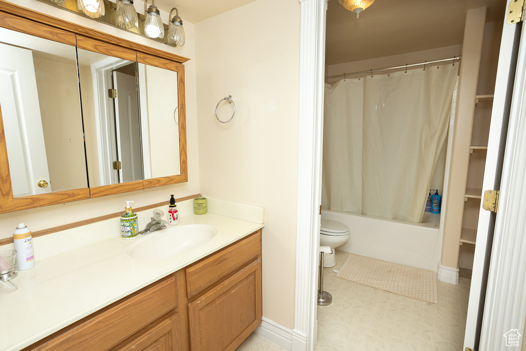 Full bathroom featuring tile patterned flooring, toilet, vanity, and shower / bathtub combination with curtain