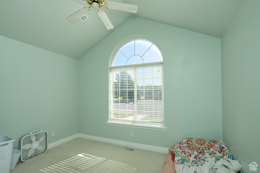 Carpeted bedroom featuring ceiling fan, lofted ceiling, and multiple windows