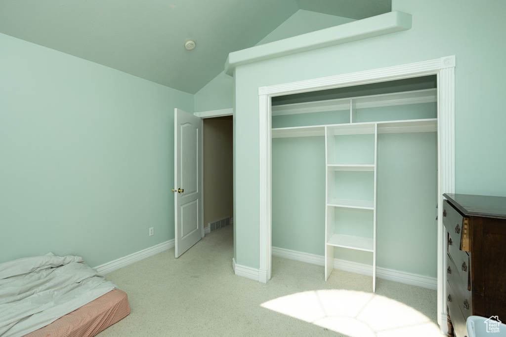 Carpeted bedroom featuring a closet and vaulted ceiling