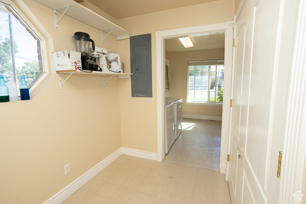 Hallway with independent washer and dryer, electric panel, and light tile patterned floors