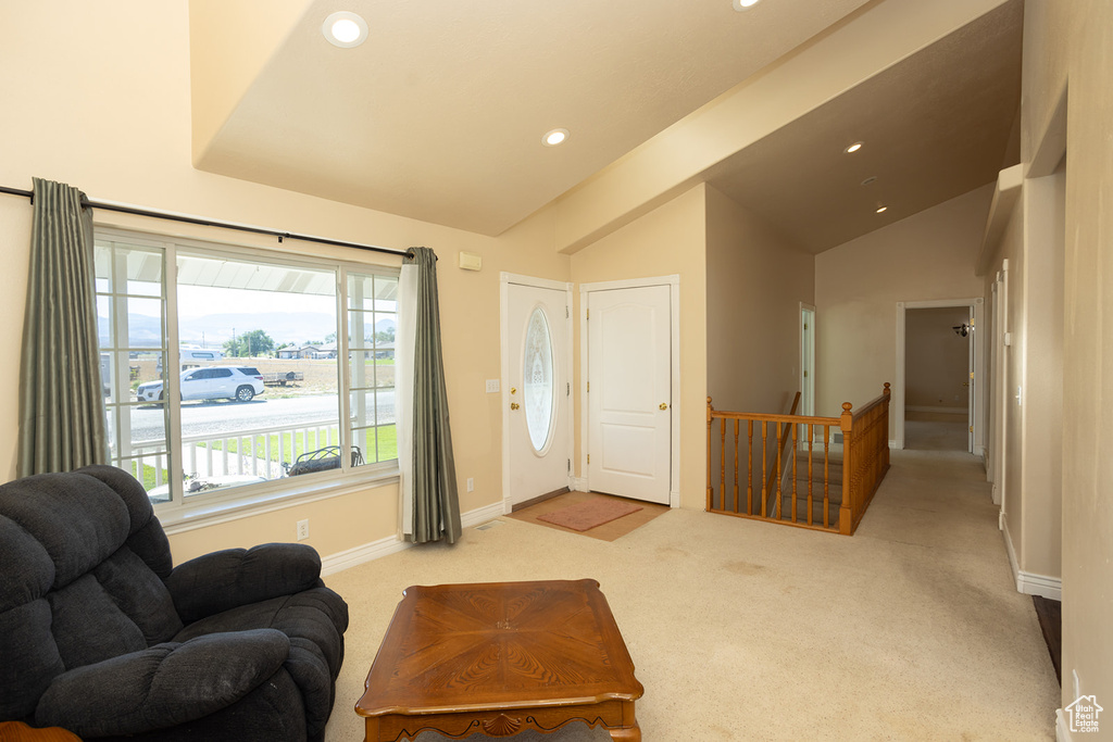 Living area featuring light carpet and high vaulted ceiling