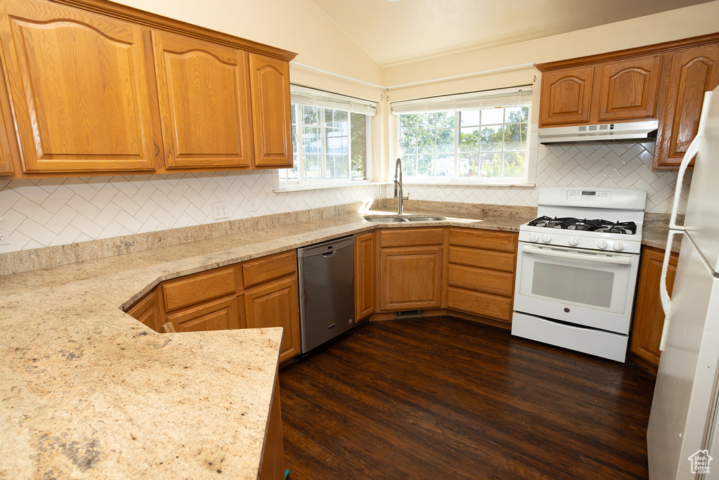 Kitchen with dark hardwood / wood-style floors, vaulted ceiling, backsplash, and white appliances