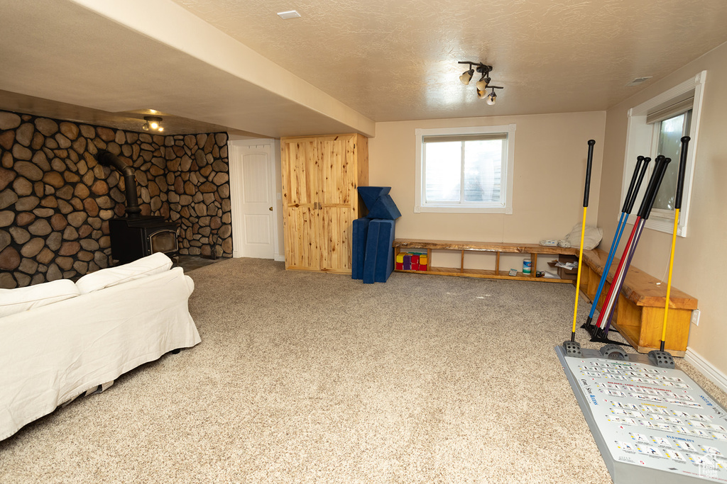 Playroom with carpet, a textured ceiling, and a wood stove