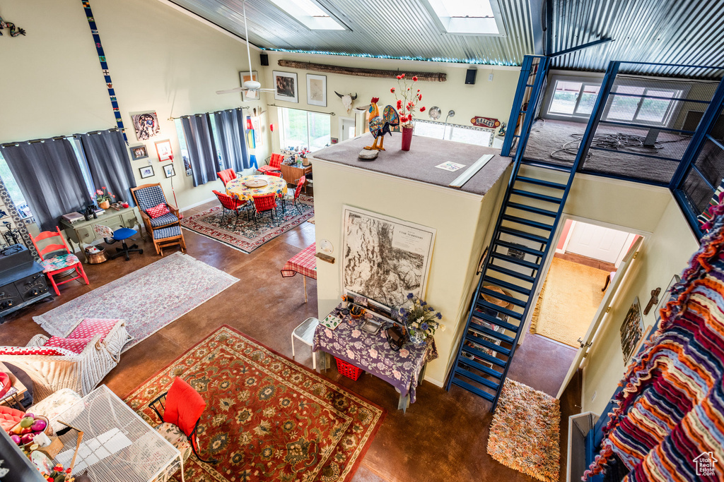 Living room featuring a wealth of natural light, high vaulted ceiling, ceiling fan, and a skylight