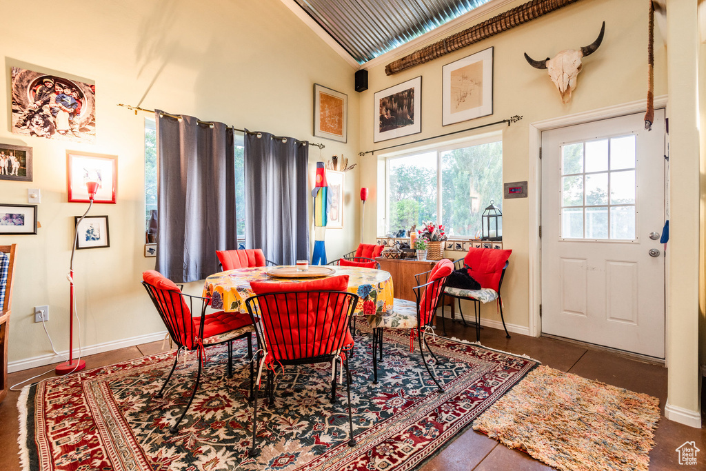 Dining space with high vaulted ceiling and dark tile patterned floors