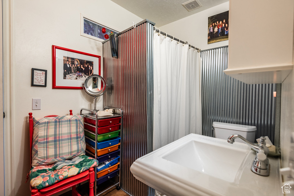 Bathroom featuring sink, toilet, and a textured ceiling