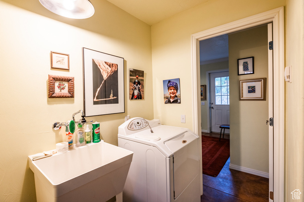 Laundry area featuring dark tile patterned flooring, sink, and independent washer and dryer