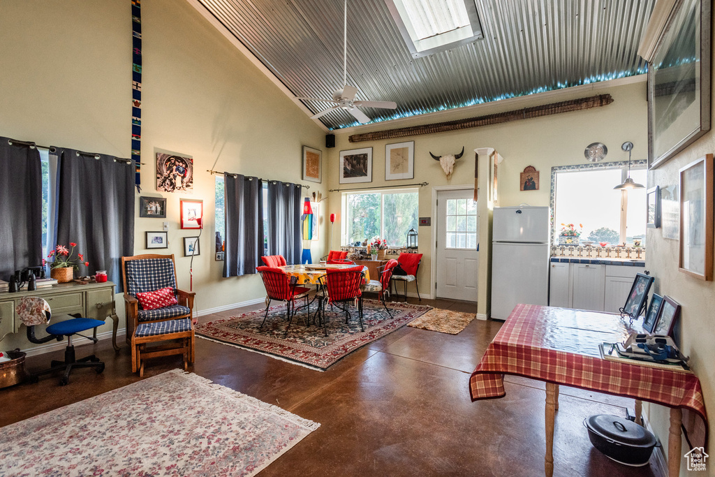 Living room with ceiling fan, concrete floors, a high ceiling, and a skylight