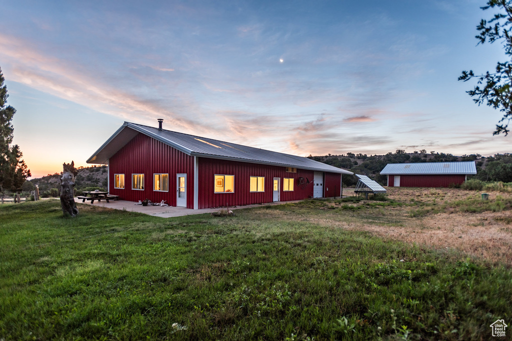 Property exterior at dusk featuring a lawn and an outdoor structure