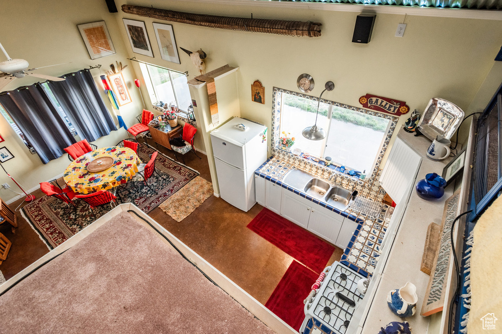 Living room featuring ceiling fan, carpet floors, and a towering ceiling