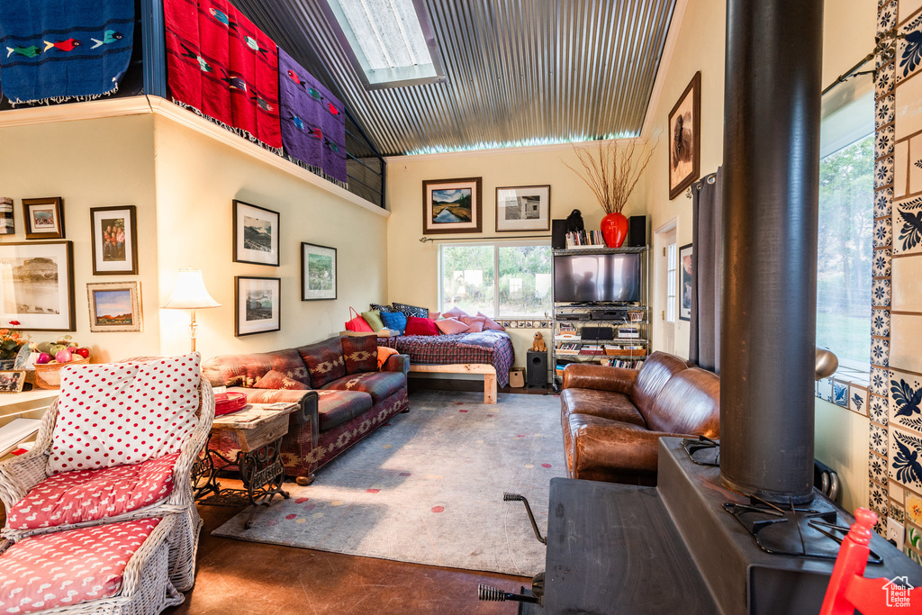 Living room featuring high vaulted ceiling, a skylight, and carpet flooring