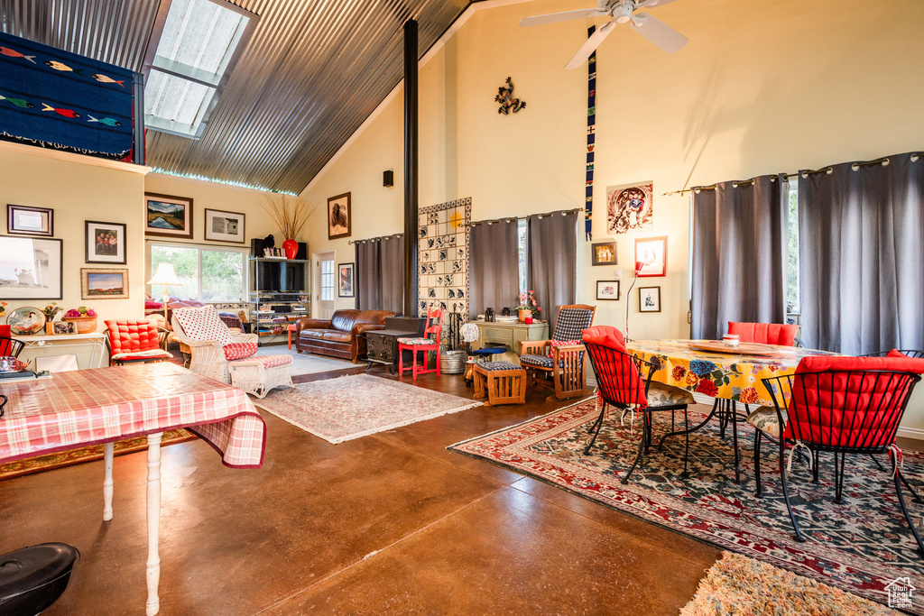 Living room featuring ceiling fan, high vaulted ceiling, a skylight, and concrete flooring