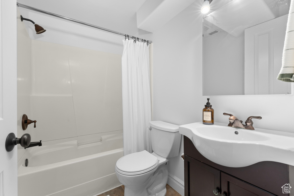 Full bathroom with toilet, shower / bathtub combination with curtain, and vanity