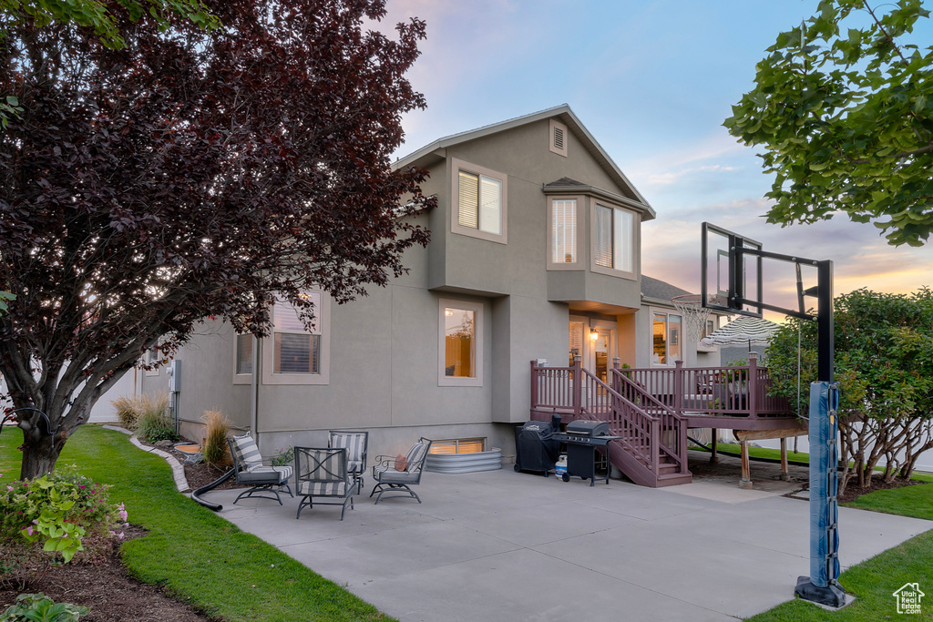 Back house at dusk featuring a patio area and a wooden deck