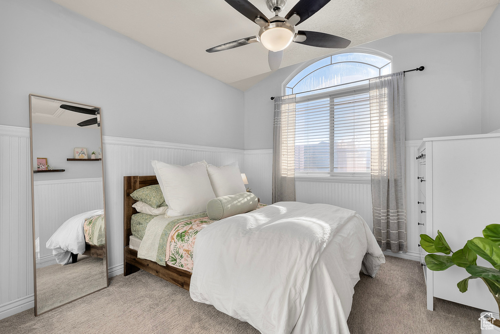 Carpeted bedroom with ceiling fan and lofted ceiling