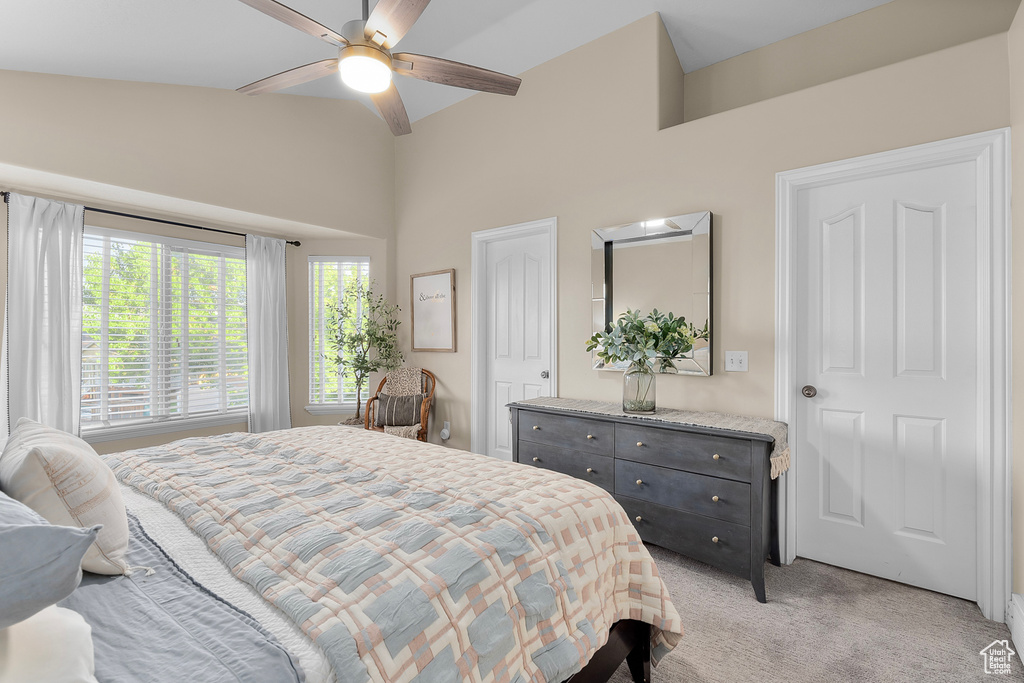 Bedroom featuring ceiling fan, vaulted ceiling, and light colored carpet