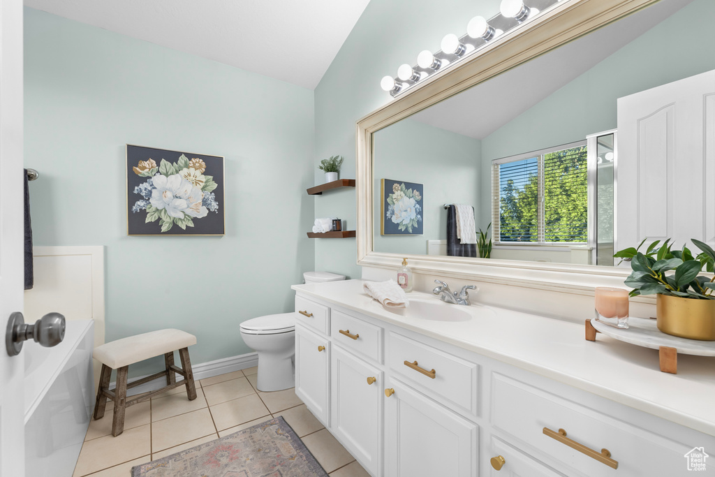 Bathroom with tile patterned floors, vaulted ceiling, vanity, and toilet