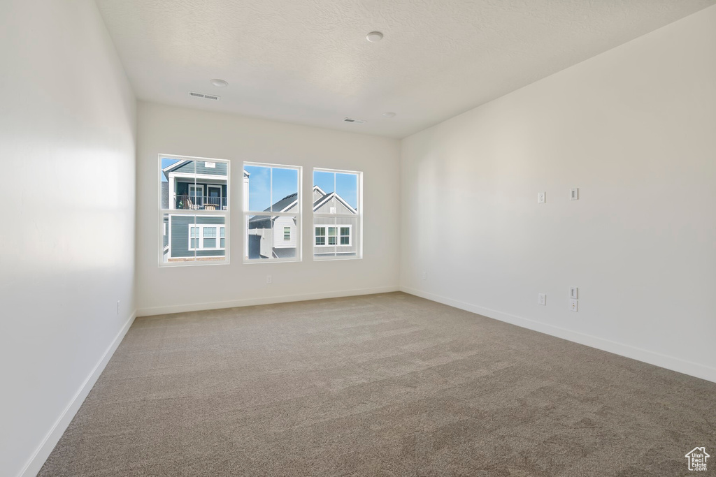Spare room featuring carpet floors, baseboards, and a textured ceiling