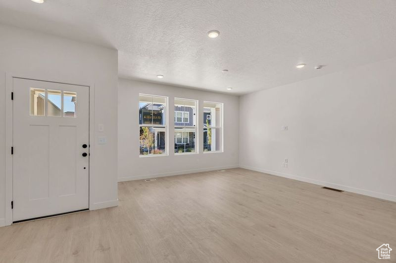 Foyer entrance with a textured ceiling, light hardwood / wood-style floors, and a healthy amount of sunlight