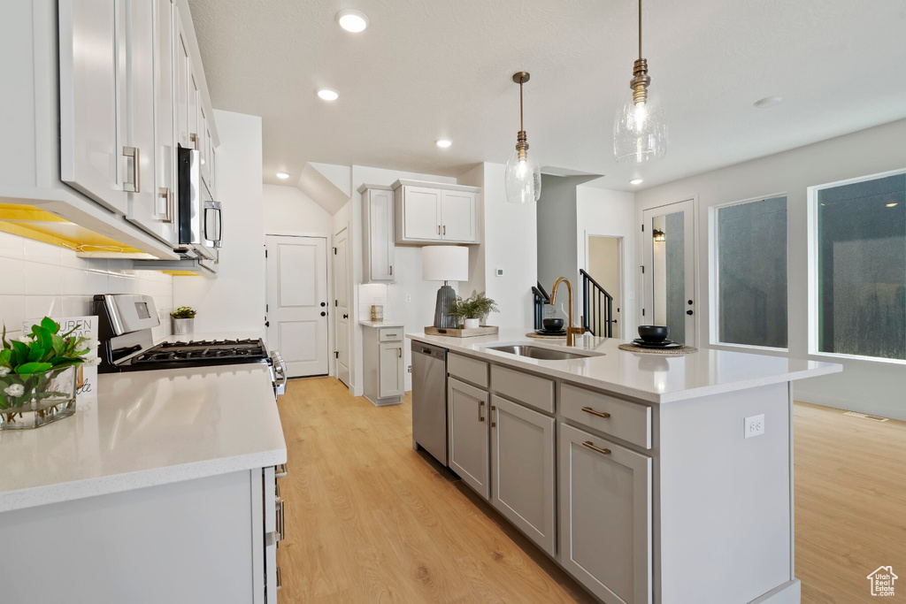 Kitchen featuring a sink, appliances with stainless steel finishes, light wood finished floors, light countertops, and recessed lighting