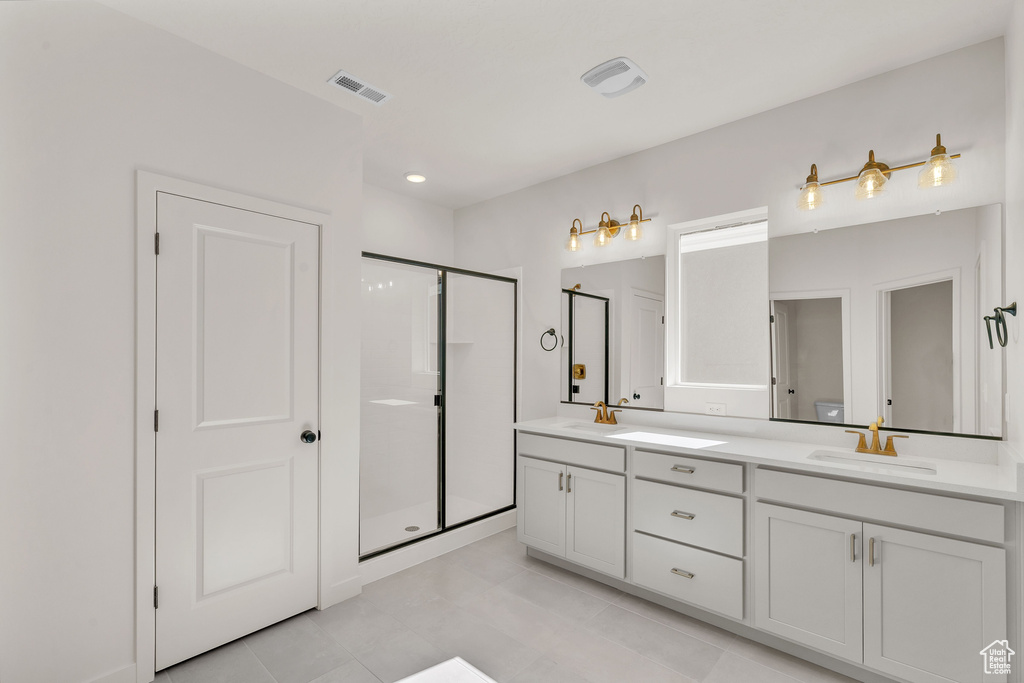 Bathroom with vanity, tile patterned flooring, and a shower with door