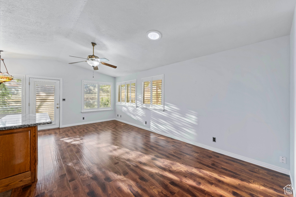 Unfurnished room featuring ceiling fan, vaulted ceiling, a textured ceiling, and dark hardwood / wood-style floors