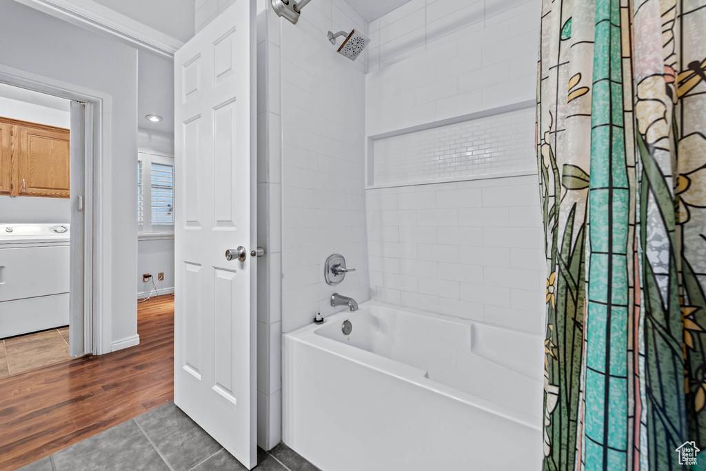 Bathroom with washer / clothes dryer, shower / bath combo with shower curtain, and wood-type flooring