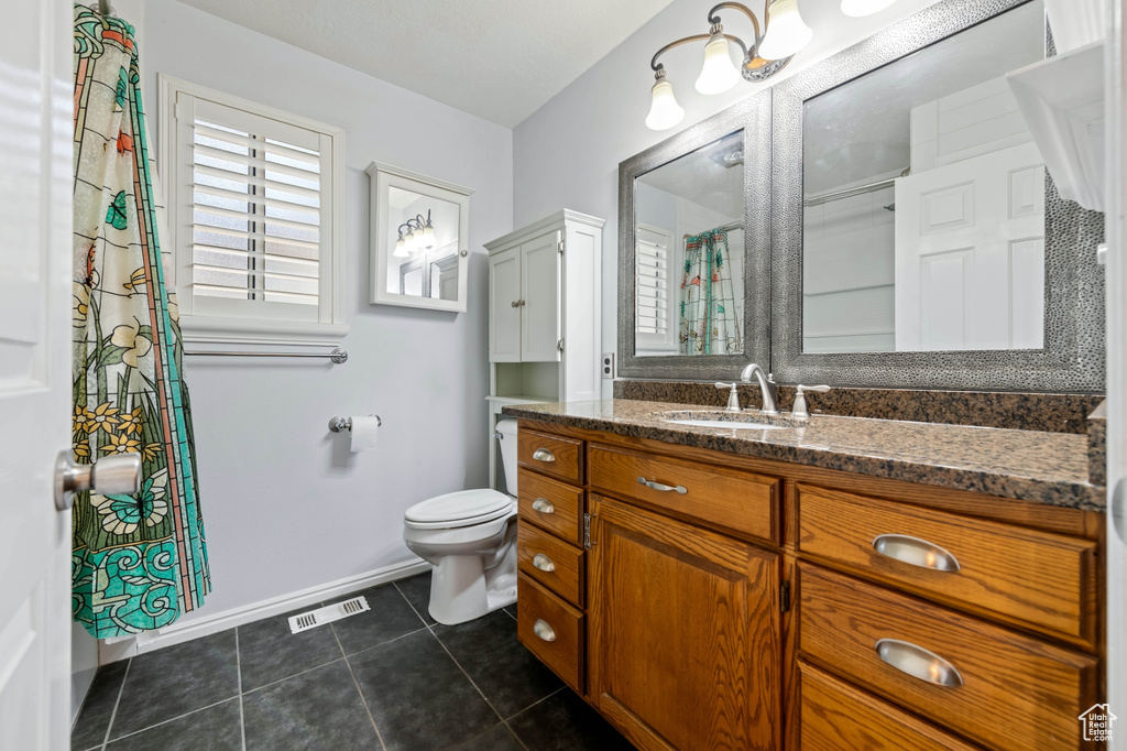 Bathroom featuring toilet, tile patterned flooring, and vanity