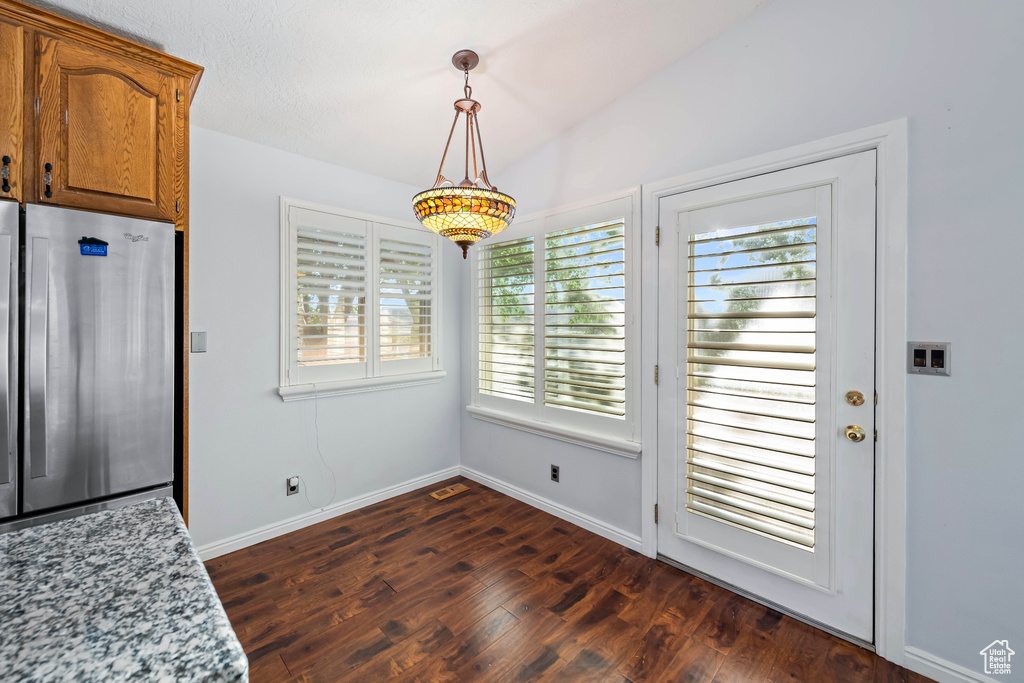 Dining room with dark wood-type flooring and vaulted ceiling