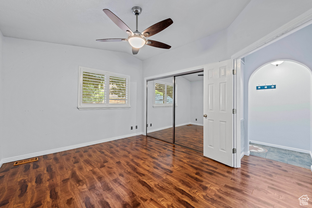 Unfurnished bedroom with a closet, ceiling fan, wood-type flooring, and lofted ceiling