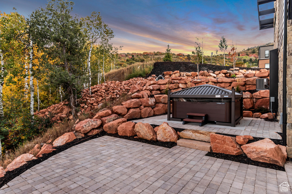 Patio terrace at dusk featuring a hot tub