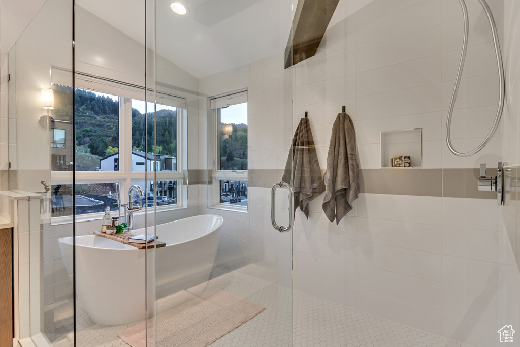 Bathroom featuring tile walls, vaulted ceiling, plus walk in shower, and tile patterned floors