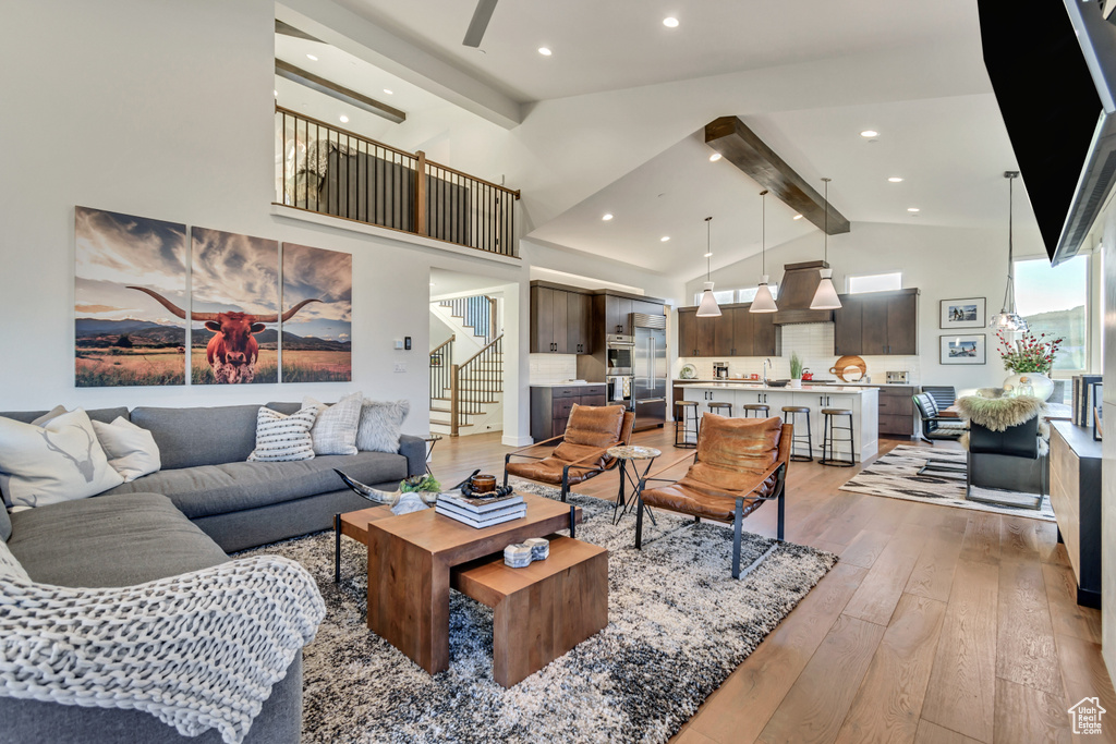 Living room with beamed ceiling, high vaulted ceiling, and light hardwood / wood-style flooring