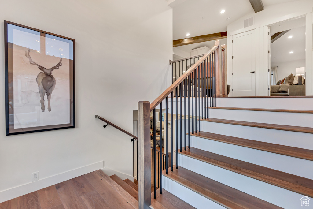 Stairs featuring lofted ceiling with beams and hardwood / wood-style flooring